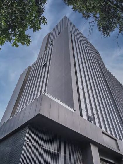 A commercial building in Thane, designed as a sleek, stepped silhouette. The structure is clad in a high-performance glass curtain wall to create soaring, day-lit office spaces with uninterrupted city views, while the ground floor is dedicated to retail.