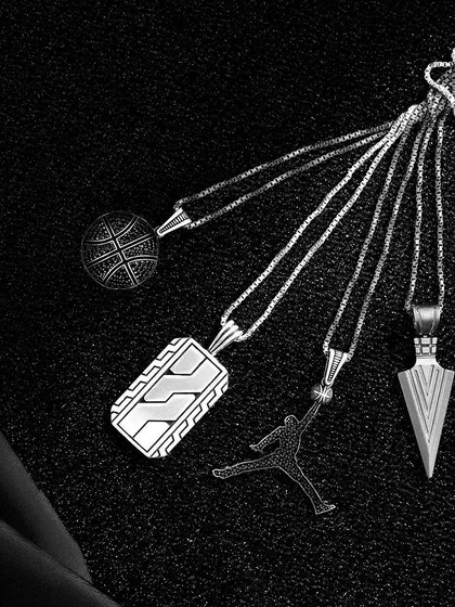 A creative flatlay of men's pendants, arranged like a fan on a black textured background. The high-contrast black and white edit gives it a timeless, classic look.