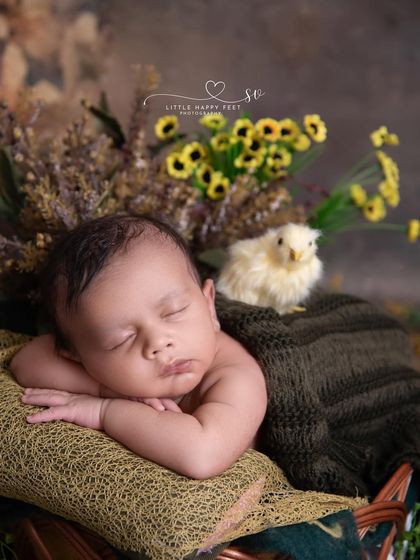 From the tiniest of beings, love blooms. This close-up shot of a baby in a froggy pose, with a tiny chick peeking over the basket, is incredibly sweet.