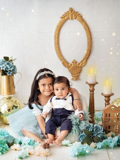 A magical sibling portrait. The sparkling lights and festive blue and gold decor create a whimsical and enchanting atmosphere for these two cuties.