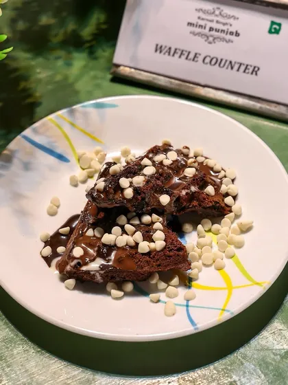 A serving of our chocolate waffle topped with white chocolate chips. We offer a variety of toppings to let guests customize their dessert.