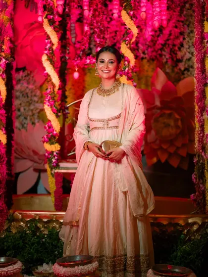 A smiling portrait of Kavya Gowda, with the vibrant pink and yellow lighting of the event creating a festive mood.