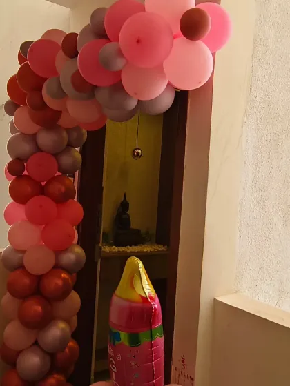 An elegant entrance decoration for a baby girl's welcome home party. The arch of pink, red, and chrome balloons creates a warm and inviting entryway.