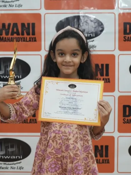 A young student proudly holds her certificate and trophy.