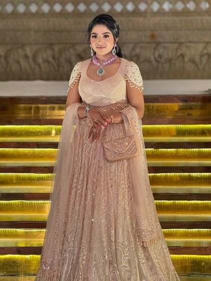 A stunning bride in a shimmering peach lehenga by Tarun Tahiliani. The makeup is elegant and sophisticated, with a focus on glowing skin.