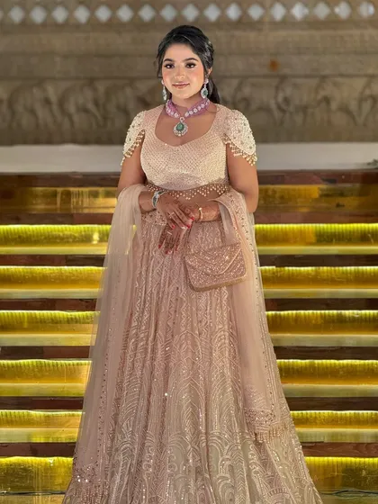 A stunning bride in a shimmering peach lehenga by Tarun Tahiliani. The makeup is elegant and sophisticated, with a focus on glowing skin.