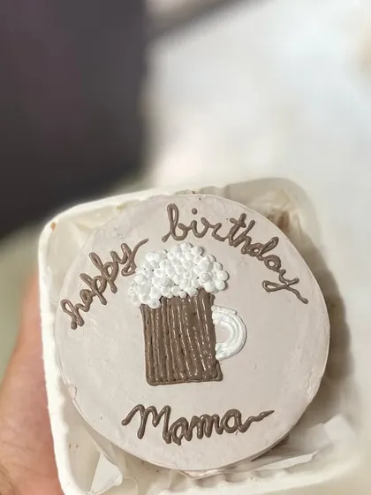 A hand-held view of the beer-themed bento cake, showing off the cute and detailed piping work.