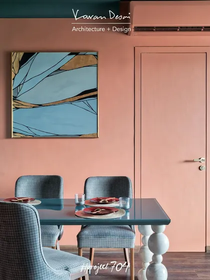 A close-up of the dining area, showing the custom table with stacked marble sphere legs. The abstract artwork on the wall picks up the colors from the room's palette, tying the whole space together.