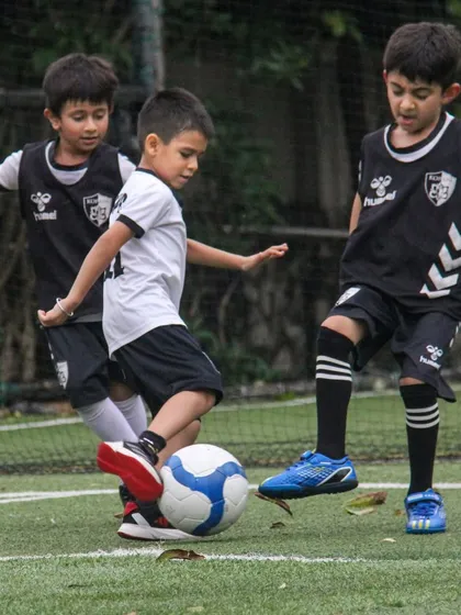 Three players converge on the ball, a great example of the high-pressure situations we create in training to improve decision-making.