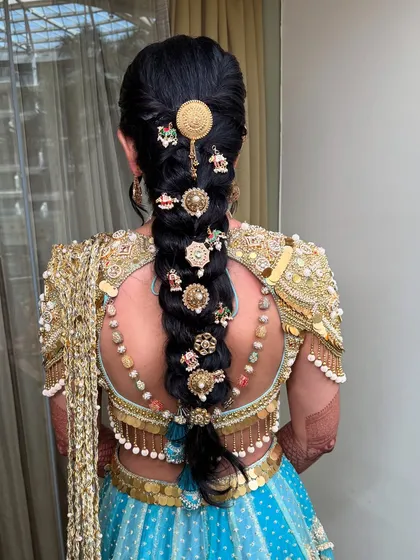 A detailed view of the elaborate braided hairstyle, adorned with traditional gold accessories.