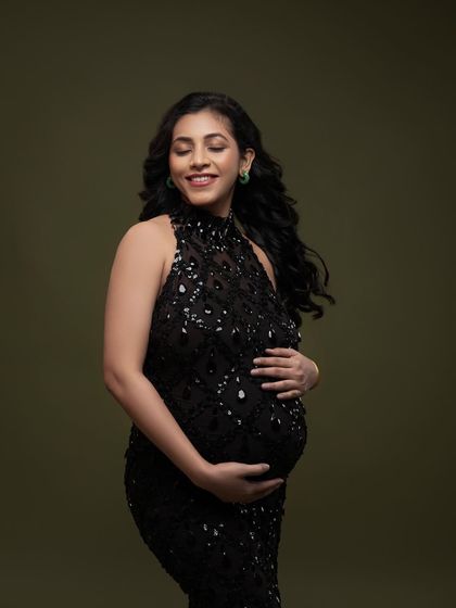A moment of quiet contemplation in a sparkling black halter gown. The olive green background provides a rich, earthy contrast to the glamorous dress.