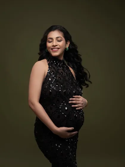 A moment of quiet contemplation in a sparkling black halter gown. The olive green background provides a rich, earthy contrast to the glamorous dress.