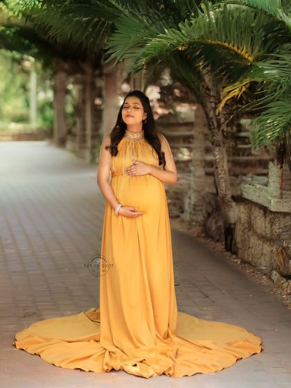 A serene outdoor portrait of an expecting mother in a flowing yellow gown, capturing a moment of peace and connection with her baby.