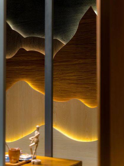 A close-up of the backlit, mountain-inspired veneer wall art, which adds a warm, ambient glow to the space.