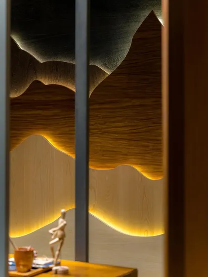 The warm light from the veneer art piece creates an intimate and inspiring atmosphere, perfect for creative discussions.
