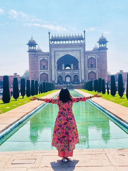 A classic tourist shot with a stylish twist. The open-armed pose in this colorful anarkali celebrates the grandeur of the Taj Mahal, creating a perfect fusion of fashion and travel.