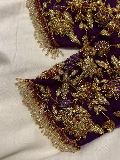 This purple net blouse was a joy to create for my dear client Sowmya's baby shower. The sheer sleeves are adorned with delicate, hand-embroidered floral vines in gold threadwork, creating a look of ethereal elegance for her special day.