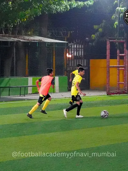 A player dribbles down the line under the floodlights during an evening training session.