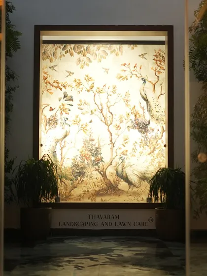 We blend art with nature to create serene focal points. This beautifully illuminated wall mural, featuring peacocks and foliage, is flanked by plants to create a captivating and peaceful entryway.
