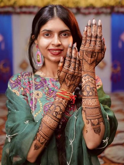 A radiant bride proudly displaying her full-arm mehandi. The design is a beautiful mix of traditional figures and intricate patterns.