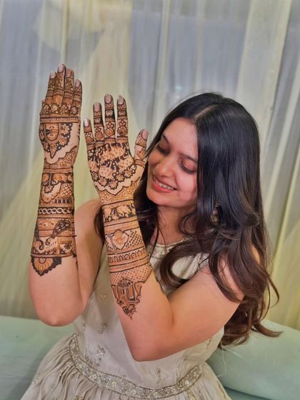 A joyful client showing off the back of her hands, which feature beautiful and dense patterns.