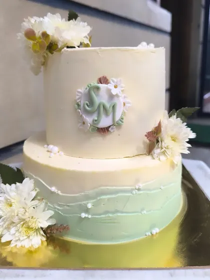 I'm in love with this sage green and white color combination for engagement cakes. This two-tier design is decorated with fresh white flowers and a custom monogram plaque for a soft, rustic, and elegant feel.