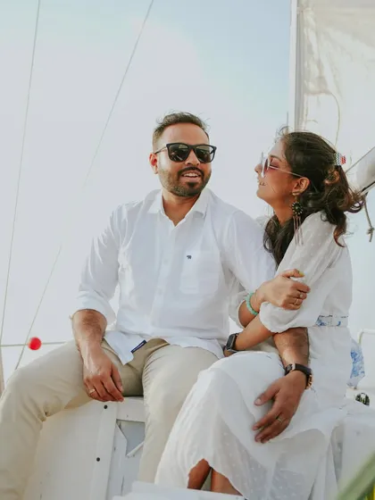 A romantic shot of a couple sharing a moment on a sailboat. The natural lighting and the backdrop of the open water create a serene and intimate portrait.