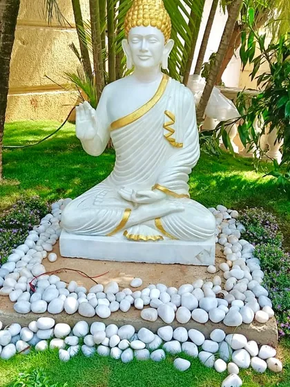 Creating a tranquil corner in a garden with a Buddha statue, surrounded by carefully selected plants and a bed of white pebbles. I focus on these details to build a specific atmosphere for my clients.