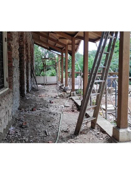 The veranda during the early stages of reconstruction. Here you can see the new wooden support pillars and the exposed load-bearing stone wall before the final finishes are applied, showing the skeleton of the restoration.