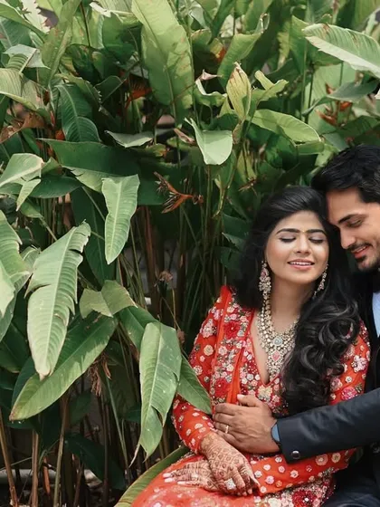 A cozy and romantic moment in a lush, green setting. The couple's embrace and happy expressions create a warm and intimate portrait, showing a softer side to their modern shoot.