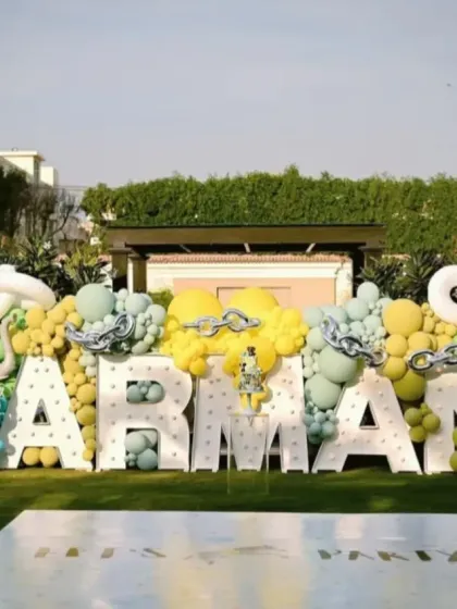 A spectacular fun fair backdrop featuring the birthday boy's name in giant LED letters, surrounded by animal props and creative balloon arrangements.