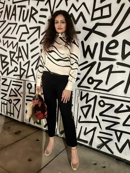 A chic, monochromatic look against a graphic background. I guide my clients on building a versatile wardrobe that includes both timeless basics and statement pieces like this patterned blouse.
