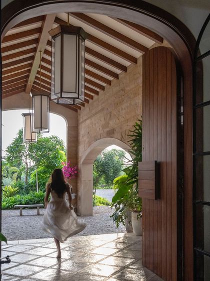 The main entrance porch, designed to feel grand yet welcoming. The large wooden door, oversized lanterns, and arched openings create a dramatic sense of arrival.