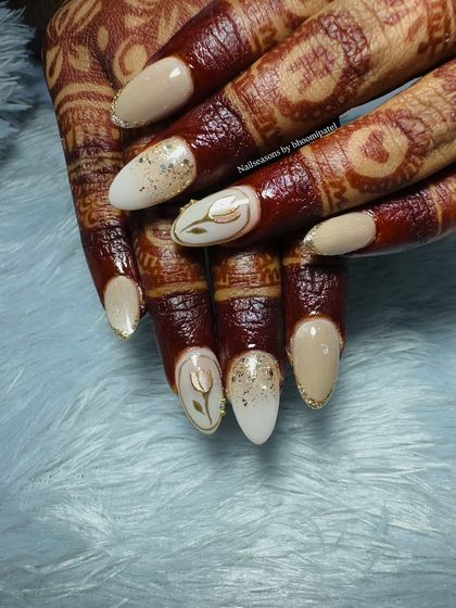 The nude and gold tones of this bridal nail art look absolutely beautiful against the deep color of her mehndi.