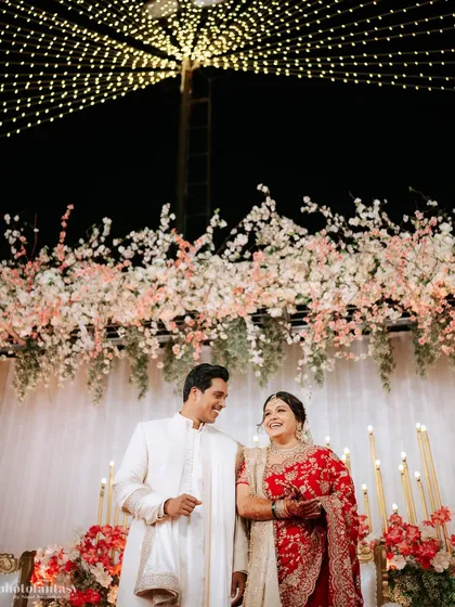 A beautiful shot of the couple under a canopy of fairy lights and flowers.
