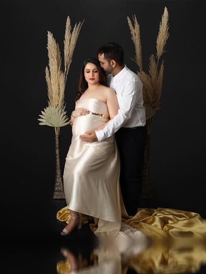 I created this fine art maternity portrait using a dark, reflective floor and dramatic lighting. The expecting mother is seated, wearing a satin gown that pools around her, creating a look of pure elegance.
