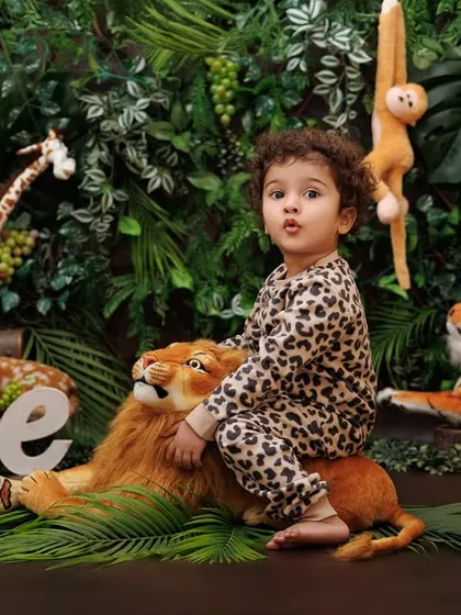 King of the jungle! A one-year-old boy confidently sits on a plush lion prop in his safari-themed session.