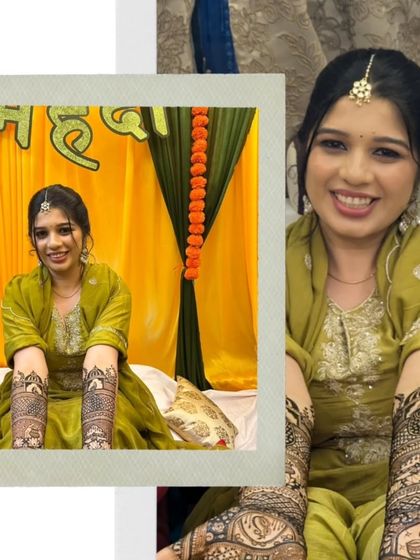 A happy bride showing off her detailed forearm henna. The design includes traditional jharokha windows and floral patterns.