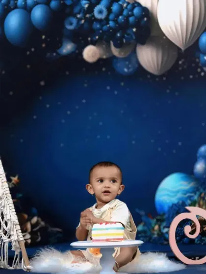 A full view of our celestial first birthday theme, featuring a baby with his cake, a macrame teepee, and a beautiful blue balloon galaxy.