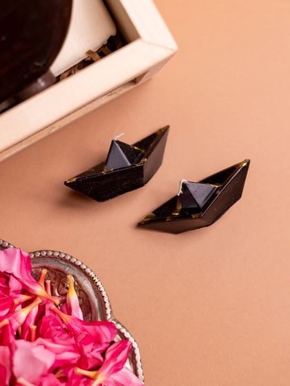 A unique detail from the 'Onasanchari' hamper: two small, boat-shaped candles. These custom candles add a warm, ambient touch that complements the overall theme of the gift box.