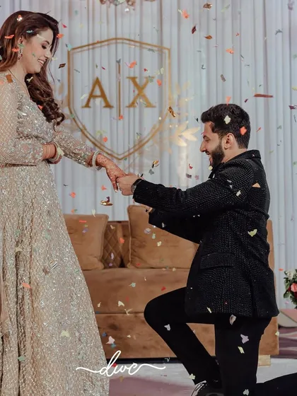 A picture-perfect proposal under a shower of confetti, with the couple's custom monogram in the background, marking their official engagement.
