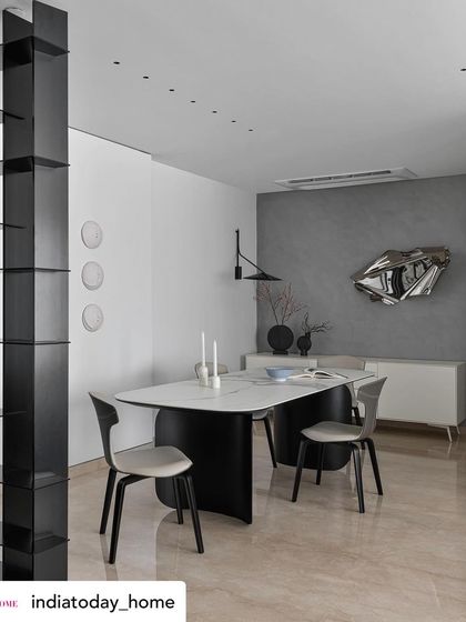 A wider view of the dining space, featured in India Today Home. The sleek black bookshelf acts as a divider while framing the view towards the art piece, creating layers and depth in this meticulously crafted home.