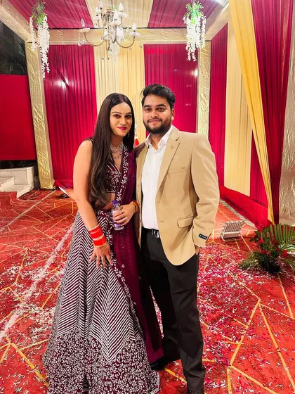 The happy couple posing for a photo. She looks stunning in the maroon chevron lehenga.