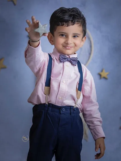 Dressed smartly in a bowtie and suspenders, this little boy holds up a star against a dreamy, night-sky backdrop. Themed studio sessions like this are a wonderful way to bring a child's imagination to life.