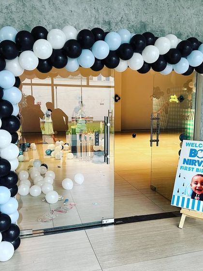 A stylish black, white, and blue balloon arch creating an inviting entrance for a Boss Baby themed party. A personalized welcome sign greets guests as they arrive.
