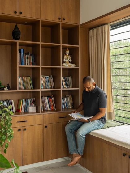 A cozy reading nook with a window seat is integrated into the custom library shelving, demonstrating thoughtful and functional space planning.
