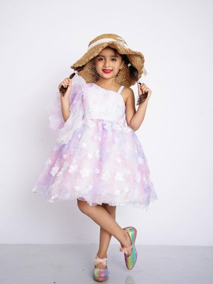 A stylish studio portrait of a young girl in a beautiful pastel dress and a straw hat, looking like a little fashionista.