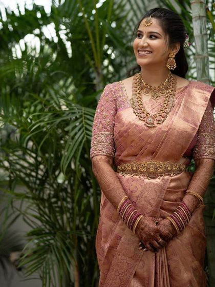A full-length view of the bride in her elegant dusty rose Kanchivaram saree, a popular color choice for modern brides.