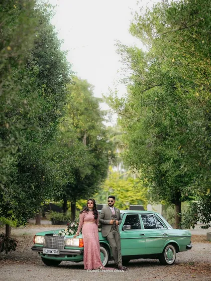A wide shot of Ameera and Richard with their vintage car, framed by lush trees. This composition highlights the grandeur and style of their post-wedding shoot.