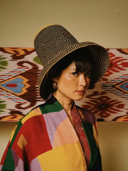 A striking portrait for House of Wandering Silk against a colorful textile backdrop. The model's pose and the vibrant patterns create a visually exciting image.